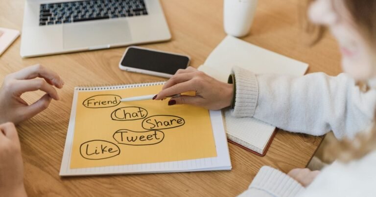 Mãos planejando publicações de redes sociais em caderno, celular e notebook